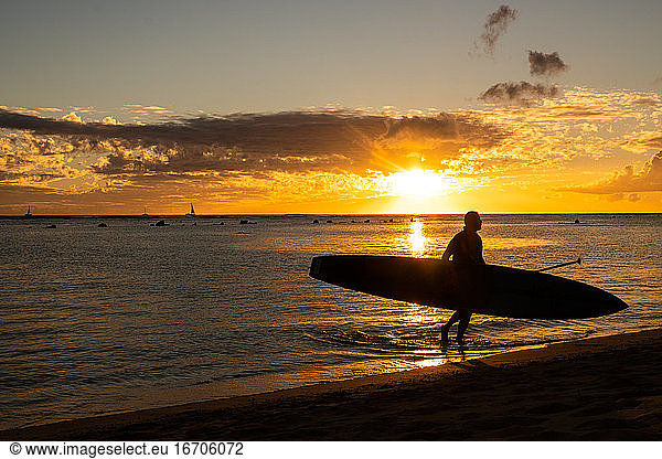 Carrying in stand up paddle board at sunset