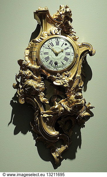 Cartel clock by Jacques Caffieri (1678-1755) Paris  c 1741. Movement Julien le Roy (1686-1759) gilt  bronze. The renowned artist Caffieri signed the case of this cartel (or wall) clock  just like a painter signs a painting. The asymmetrical Rococo case shows the figure of Diana  goddess of the moon  looking down tenderly upon the sleeping Endymion. They are set in an imaginary framework of rocoilles  plants  architectural elements and abstract motifs.