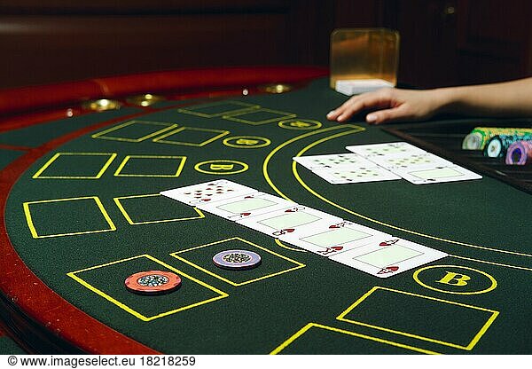Casino black jack table with chips and cards. Winning combination. Hand of Croupier behind gambling table