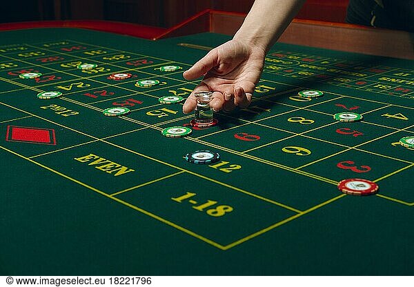 Casino roulette table with chips and cards. Winning combination. Hand of Croupier behind gambling table