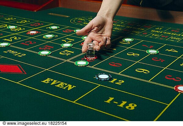 Casino roulette table with chips and cards. Winning combination. Hand of Croupier behind gambling table