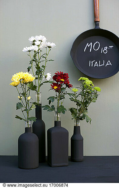 Cast iron frying pan and black bottles with chrysanthemums