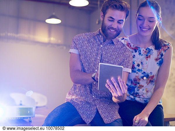 Casual businessman and businesswoman sharing digital tablet in office