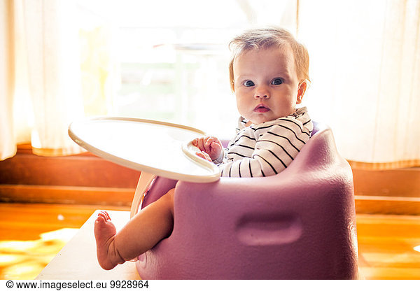 Caucasian baby girl sitting in high chair