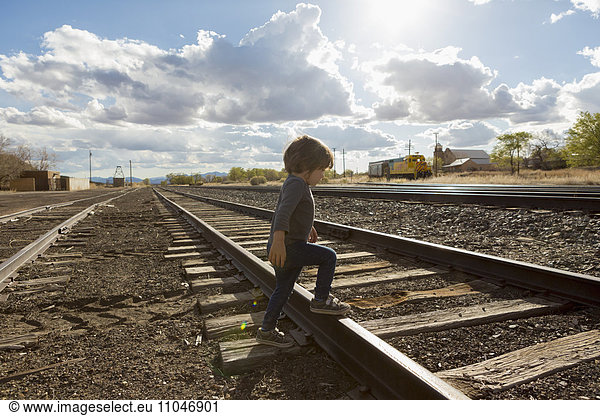 Caucasian boy crossing railroad tracks