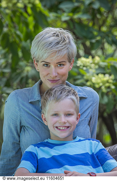 Caucasian boy leaning on mother outdoors