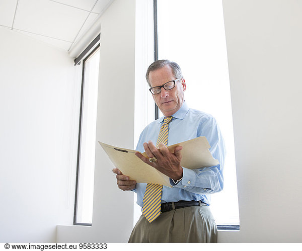 Caucasian businessman reading folder in office