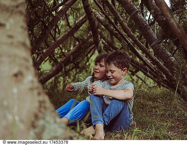 caucasian child in a hut made of branches and leaves