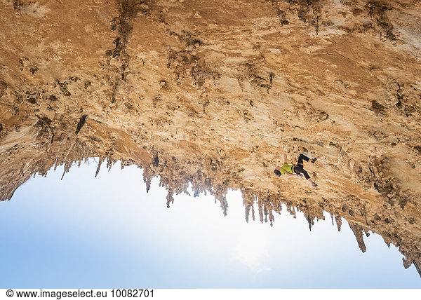 Caucasian climber scaling rock wall