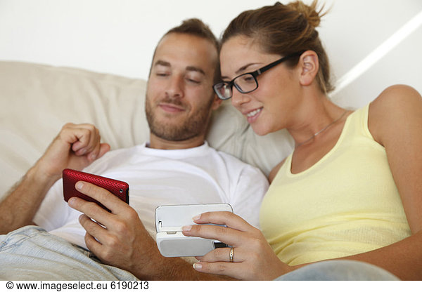 Caucasian couple laying in bed with cell phones