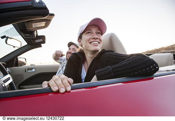 Caucasian couple parked in their sports car convertible.