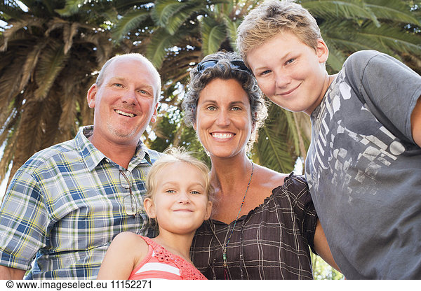 Caucasian family smiling under palm tree