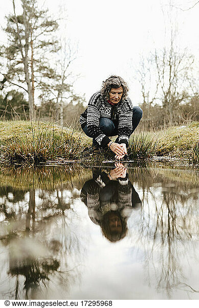 Caucasian female hiker washing hands in lake at forest