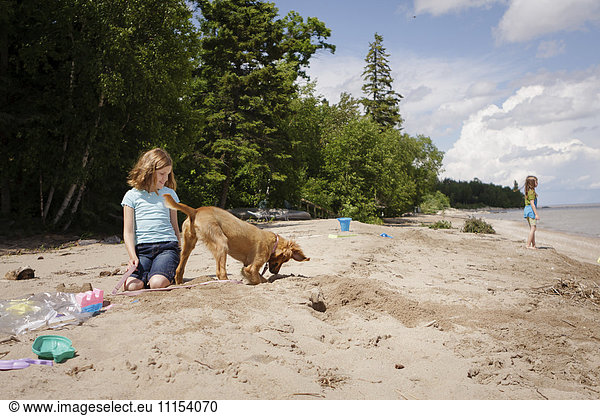 Caucasian girl and puppy playing on beach