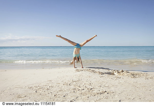 Caucasian girl doing cartwheel on beach