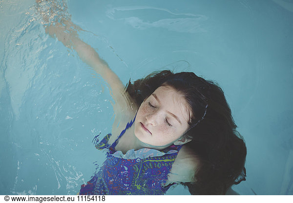 Caucasian girl floating in swimming pool