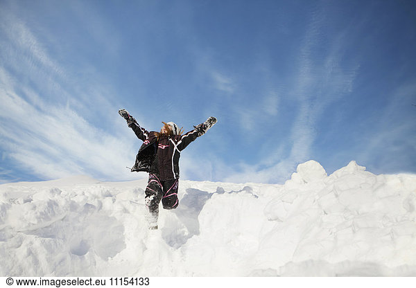 Caucasian girl jumping on snowy hillside