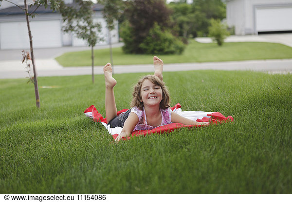 Caucasian girl laying on lawn in suburban neighborhood