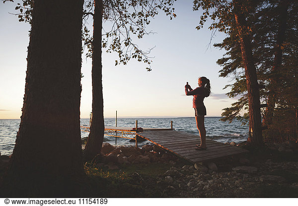 Caucasian girl photographing sunset and lake