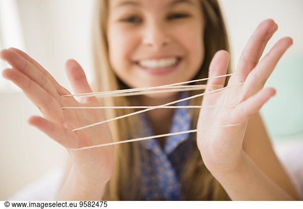 Caucasian girl playing cats cradle game