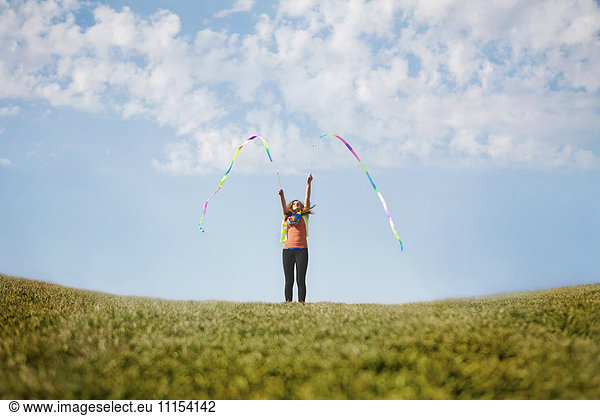 Caucasian girl playing with ribbons on hilltop
