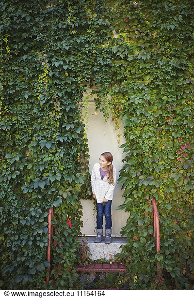 Caucasian girl standing at ivy wall