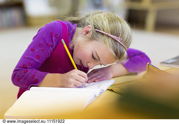 Caucasian girl writing in classroom