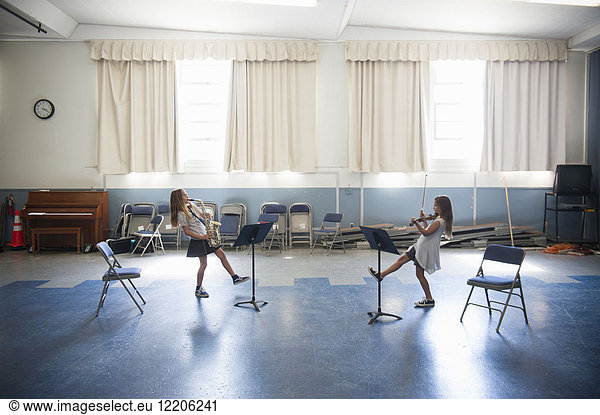 Caucasian girls practicing violins and dancing