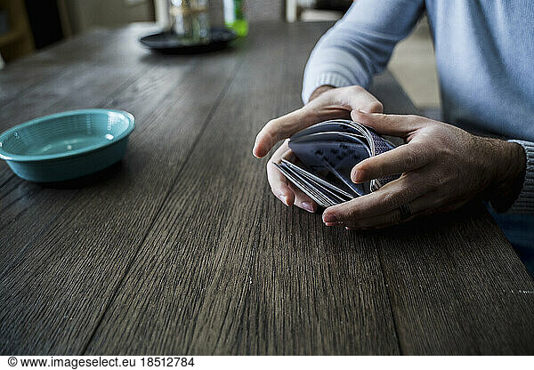 Caucasian Man Shuffling a Deck of Playing Cards at Dining Table