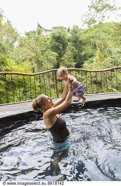 Caucasian mother and baby playing in pool