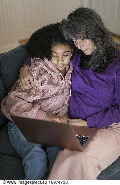 Caucasian mother  bi-racial daughter on couch watching movie together