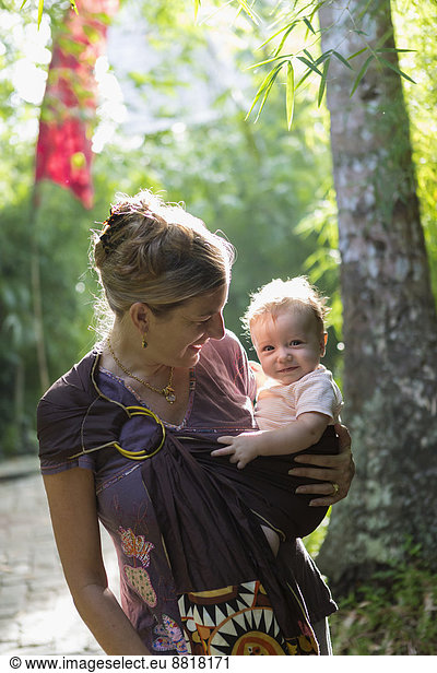 Caucasian mother carrying baby in rainforest