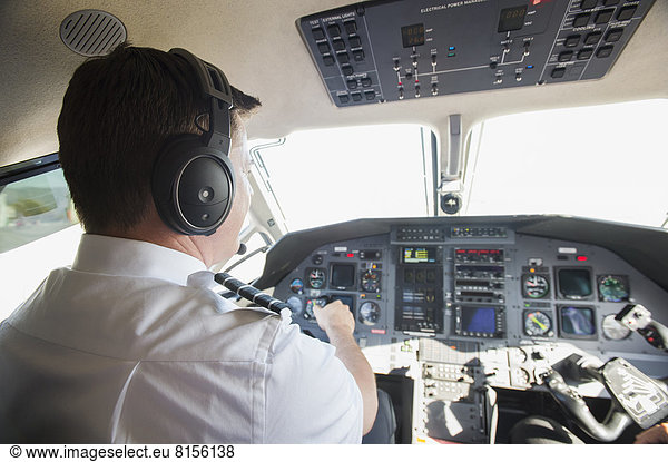Caucasian pilot working in airplane cockpit