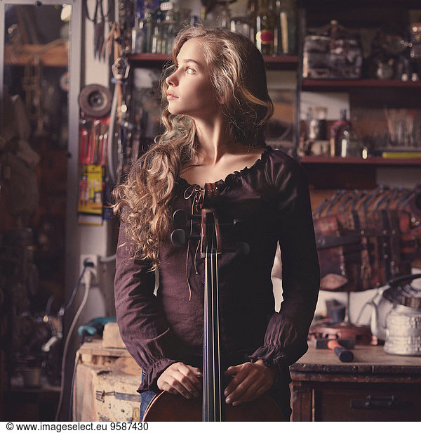 Caucasian teenage girl holding musical instrument in workshop