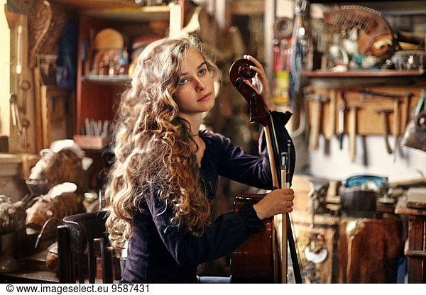 Caucasian teenage girl holding musical instrument in workshop