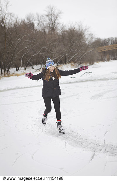 Caucasian teenage girl ice skating on frozen lake