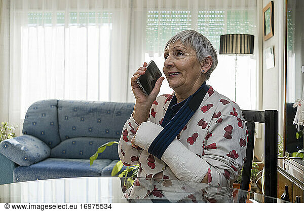 Caucasian white-haired elderly woman with broken arm  sitting at home