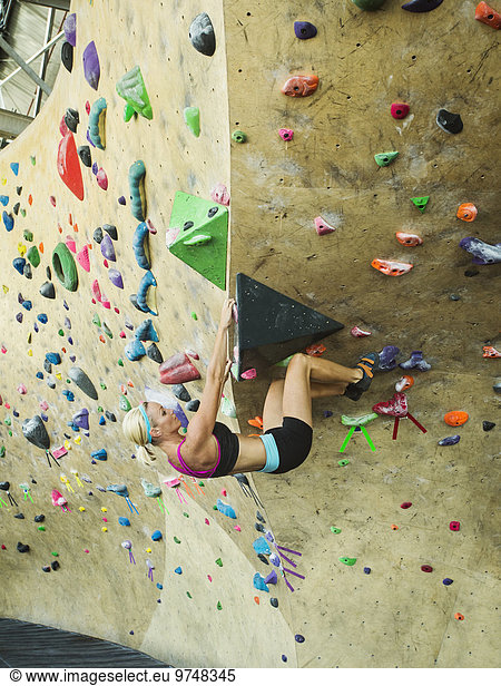 Caucasian woman climbing indoor rock wall