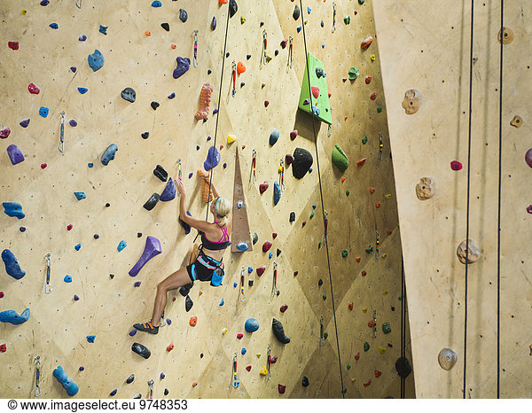 Caucasian woman climbing indoor rock wall