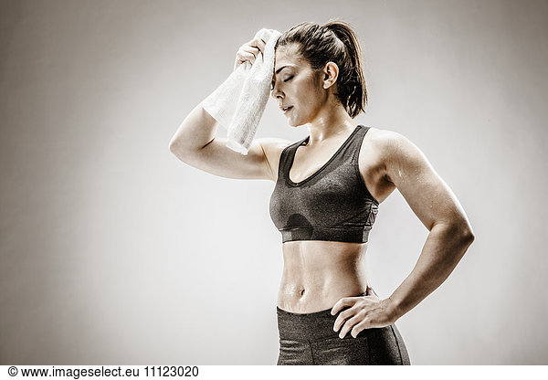Caucasian woman wiping sweat from forehead