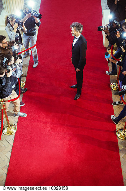 Celebrity being photographed by paparazzi photographers at red carpet event