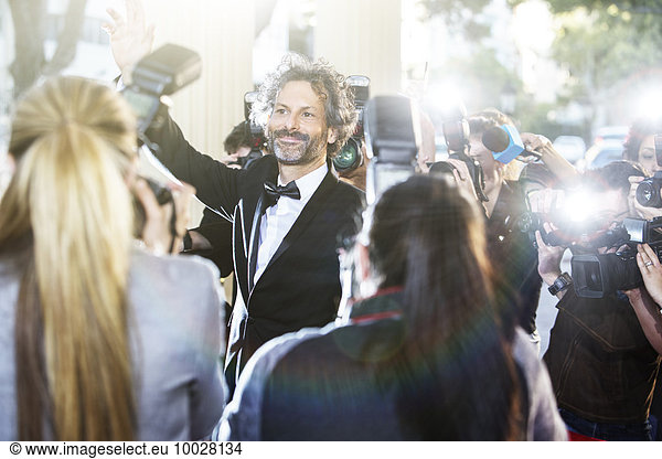 Celebrity waving at paparazzi photographers at event