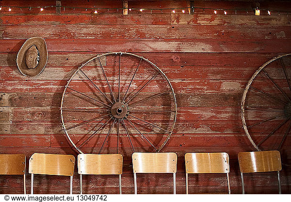 Chairs against wheels hanging on wooden wall