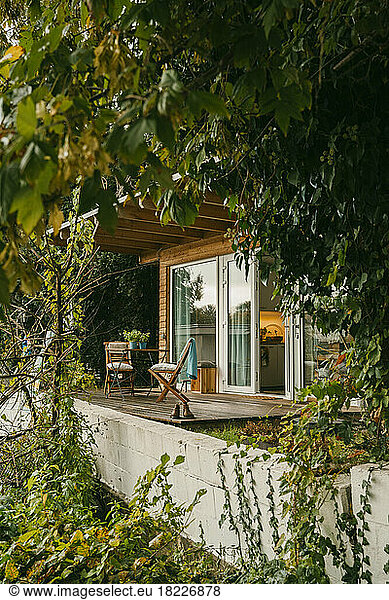 Chairs on wooden porch amidst plants outside house