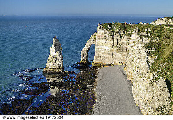 Chalk cliffs with natural arch near blue sea
