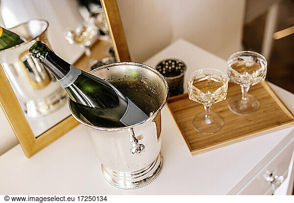 Champagne bottle in bucket with glass on table