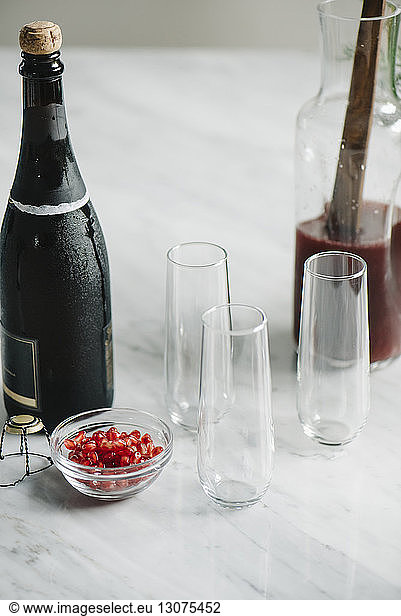 Champagne bottle with drinking glasses and pomegranate on kitchen island