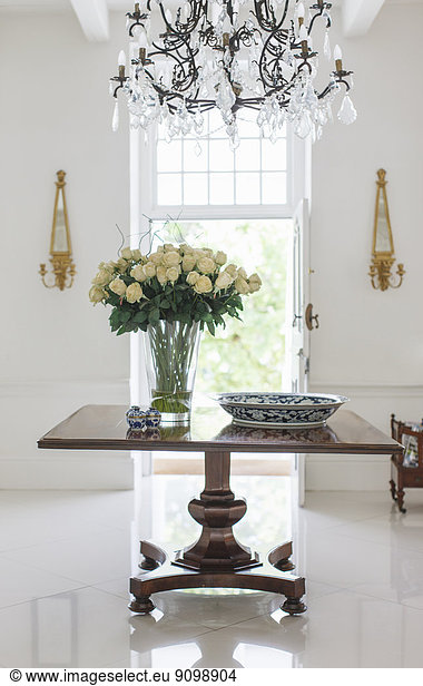 Chandelier over bouquet on table in luxury foyer