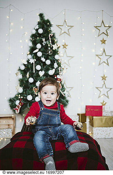Cheerful baby boy with mouth open playing while sitting at home during Christmas