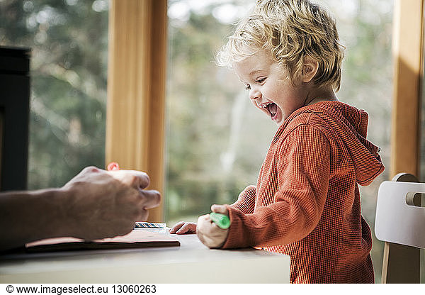 Cheerful boy learning to write while sitting by father at home